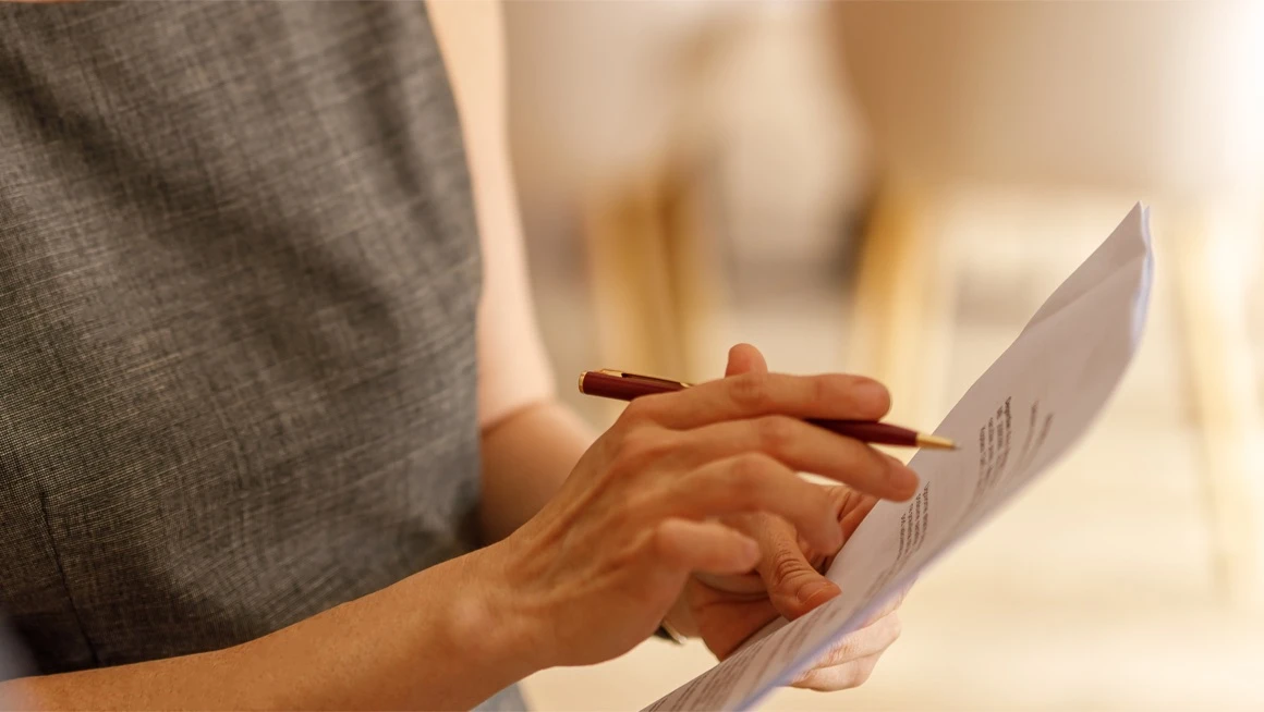 A person reviewing a document with a pen in hand
